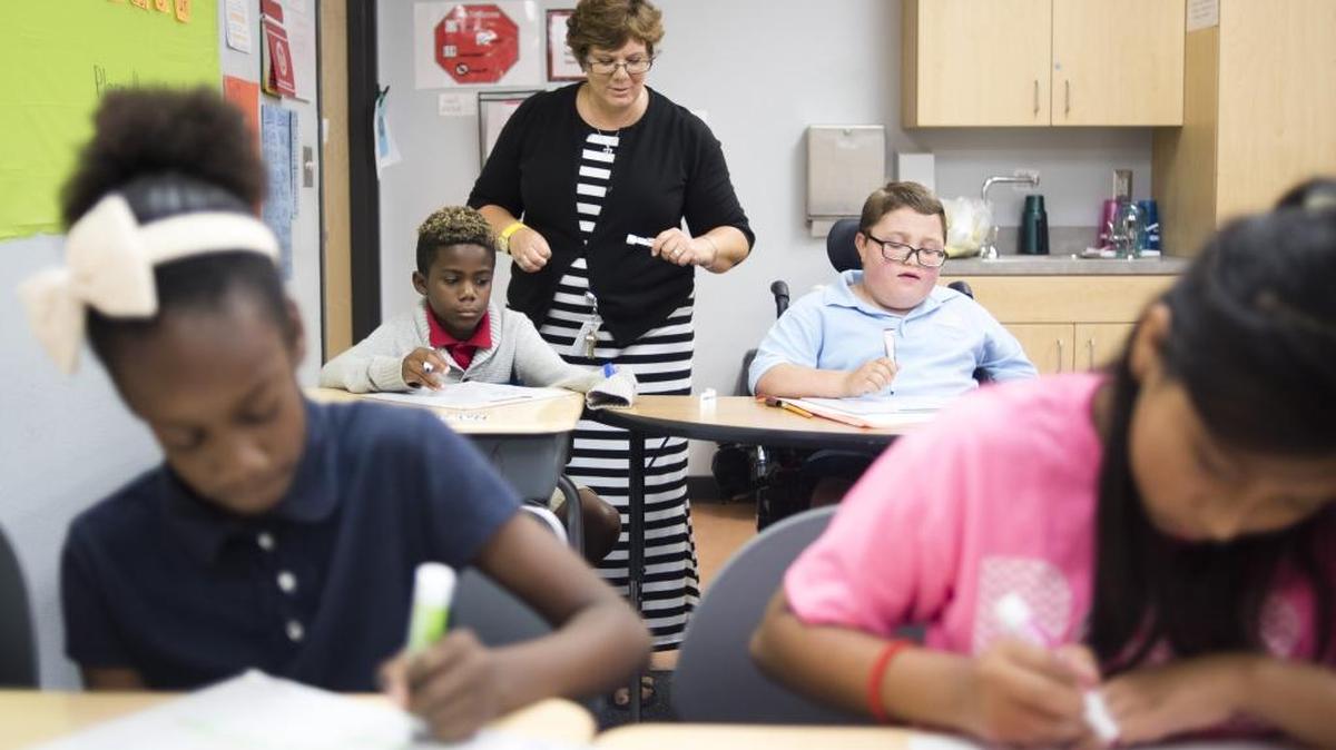 Julie McCarthy helps students solve math problems during her inclusion class on Friday afternoon at G.D. Rogers Garden Elementary School in Bradenton.