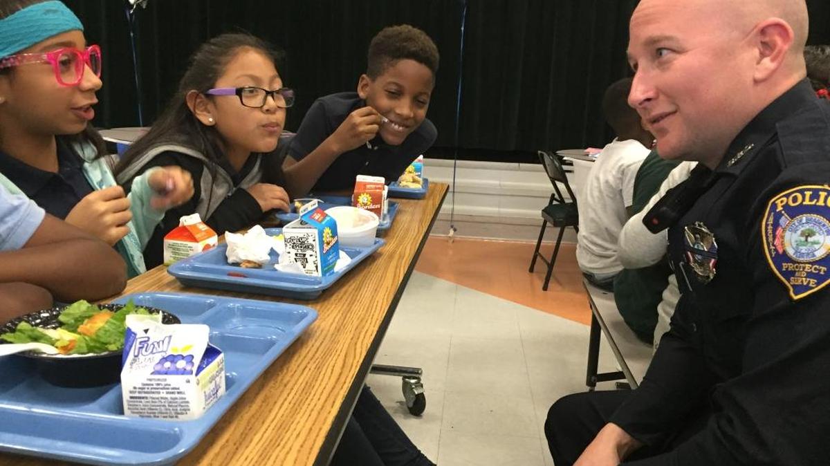 Ross Johnson, a field training officer with the Bradenton Police Department, chatted with Samira Christopher, 10, during lunch Friday at Rogers-Garden Bullock Elementary School.