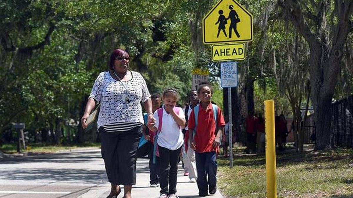In this file photo, aide Carla Range walks Manatee Elementary students down the sidewalk to cross S.R. 64 after school let out for the day.