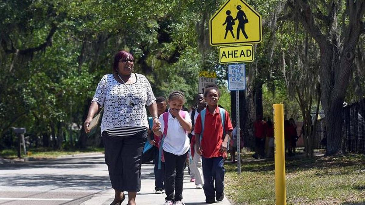 Teacher’s aide Carla Range walks Manatee Elementary School students along a sidewalk last spring. FDOT has approved $734,000 to improve walking conditions to and from school through its Schools to Sidewalks program, but the project isn’t scheduled until 2023.