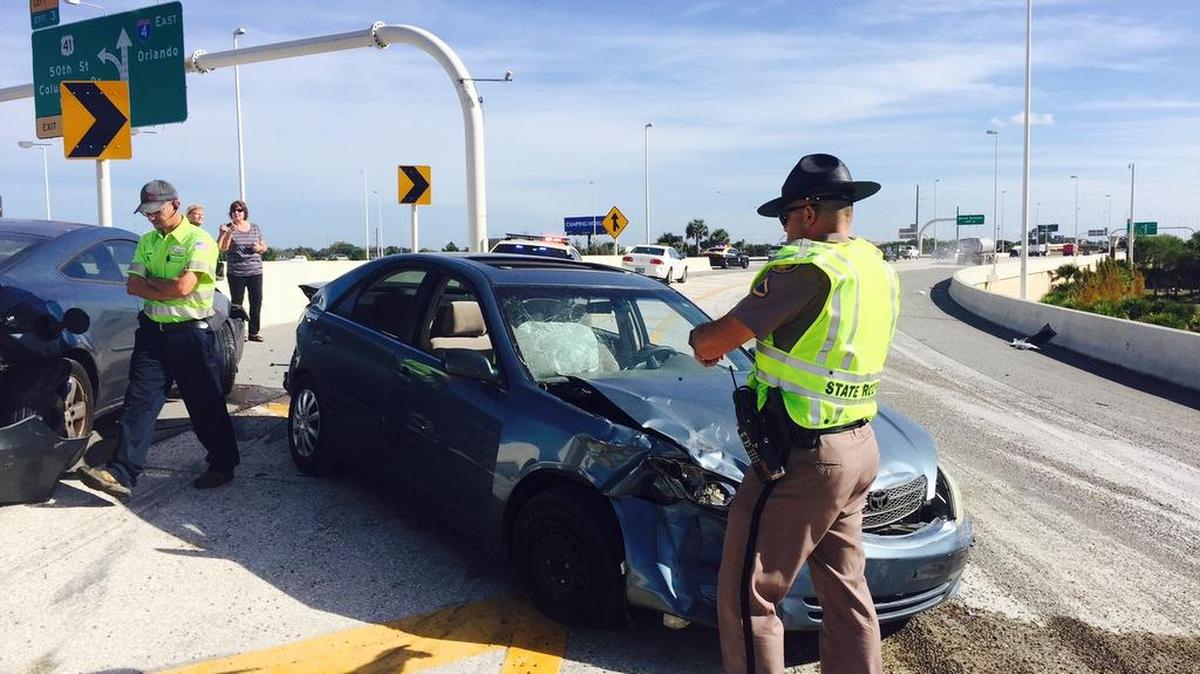 A Florida Highway Patrol trooper surveys the third car involved in the three-car crash caused by spilled gravel on the northbound ramp to Interstate 4 Tuesday morning.
