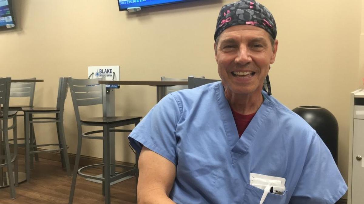 Many of his patients smile at Dr. Paige Pennebacker, above, moments before they go into breast cancer surgery at Blake Medical Center because of the cap he always wears with pink ribbons which denotes breast cancer awareness.