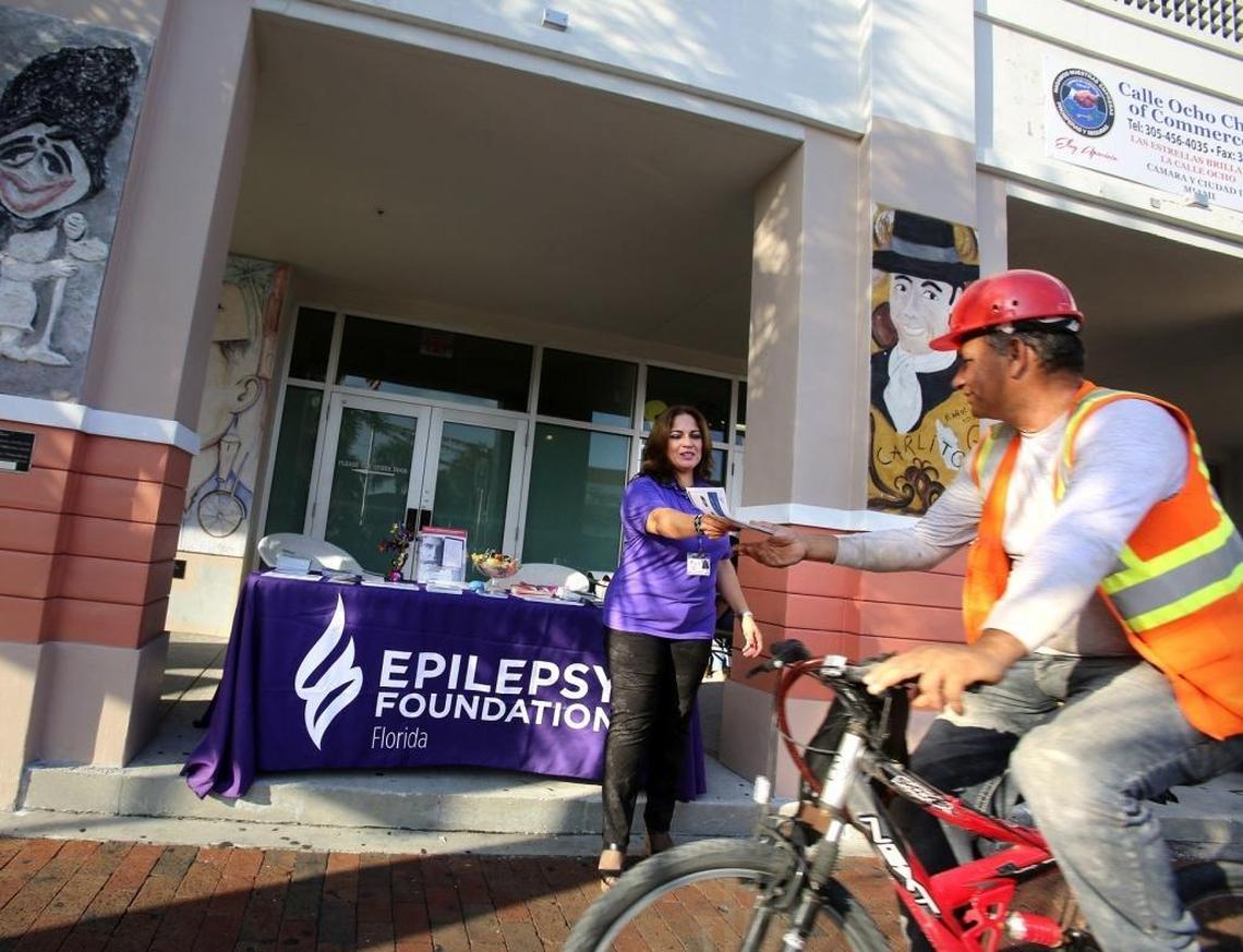 Velkis Silva, an enrollment counselor with the Epilepsy Foundation of Florida, offers printed materials to a man on a bicycle in Miami’s Little Havana In October 2015.