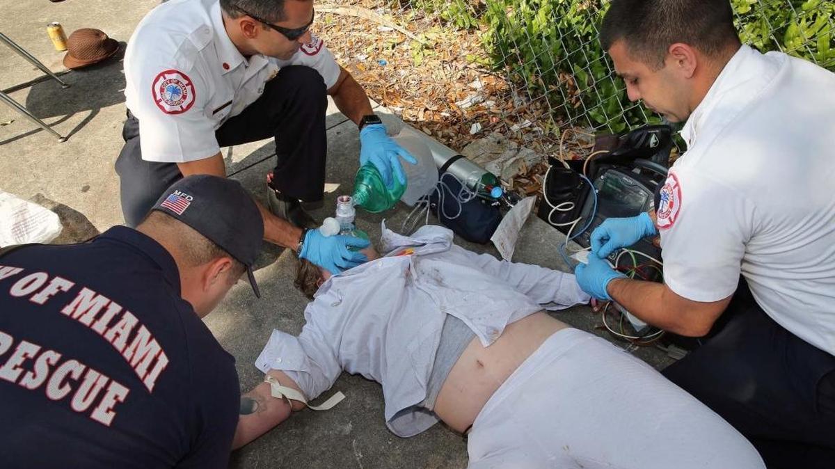 Captain Tony Milan, and battalion commander for City of Miami Fire Rescue, upper left, works on an overdose victim in Overtown last month.