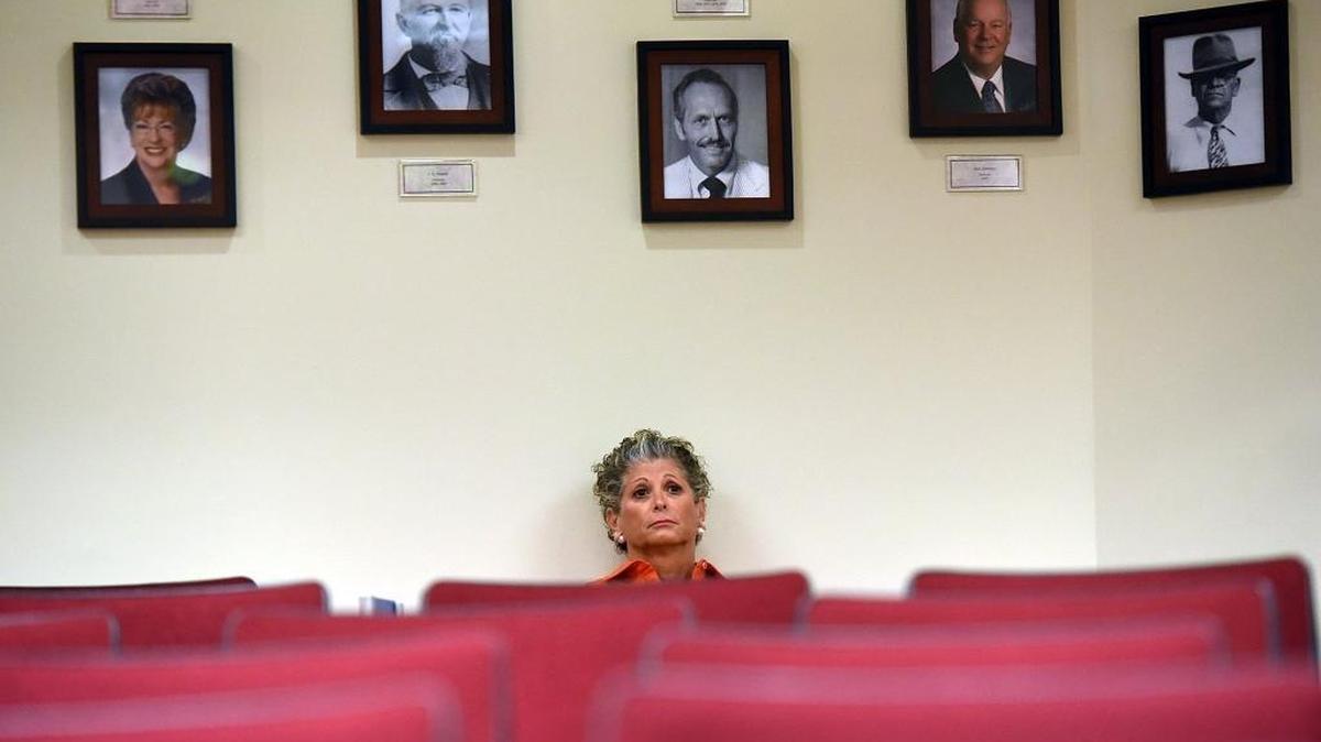 Manatee County Commissioner Robin DiSabatino, sitting beneath framed photos of former commissioners, asks her fellow commissioners to reimburse her for legal fees incurred in a lawsuit.