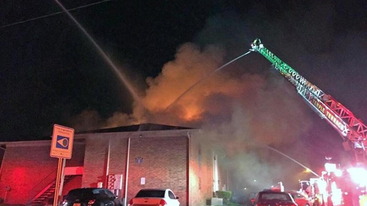 Area firefighters use ladders to put water on a blaze at the Park at Monument Terrace Apartments in Temple Terrace early Sunday morning.