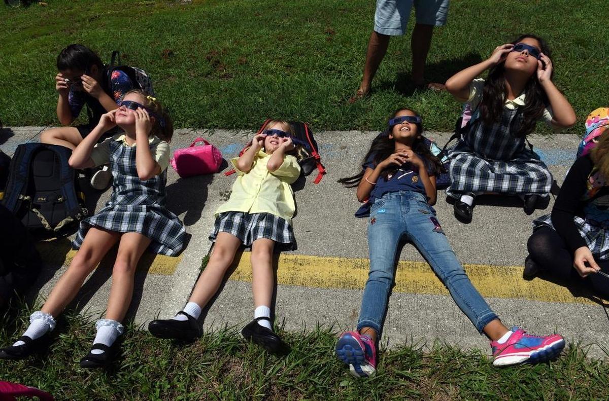 Students lie on the sidewalk to watch the solar eclipse at St. Joseph's Catholic School in Bradenton.