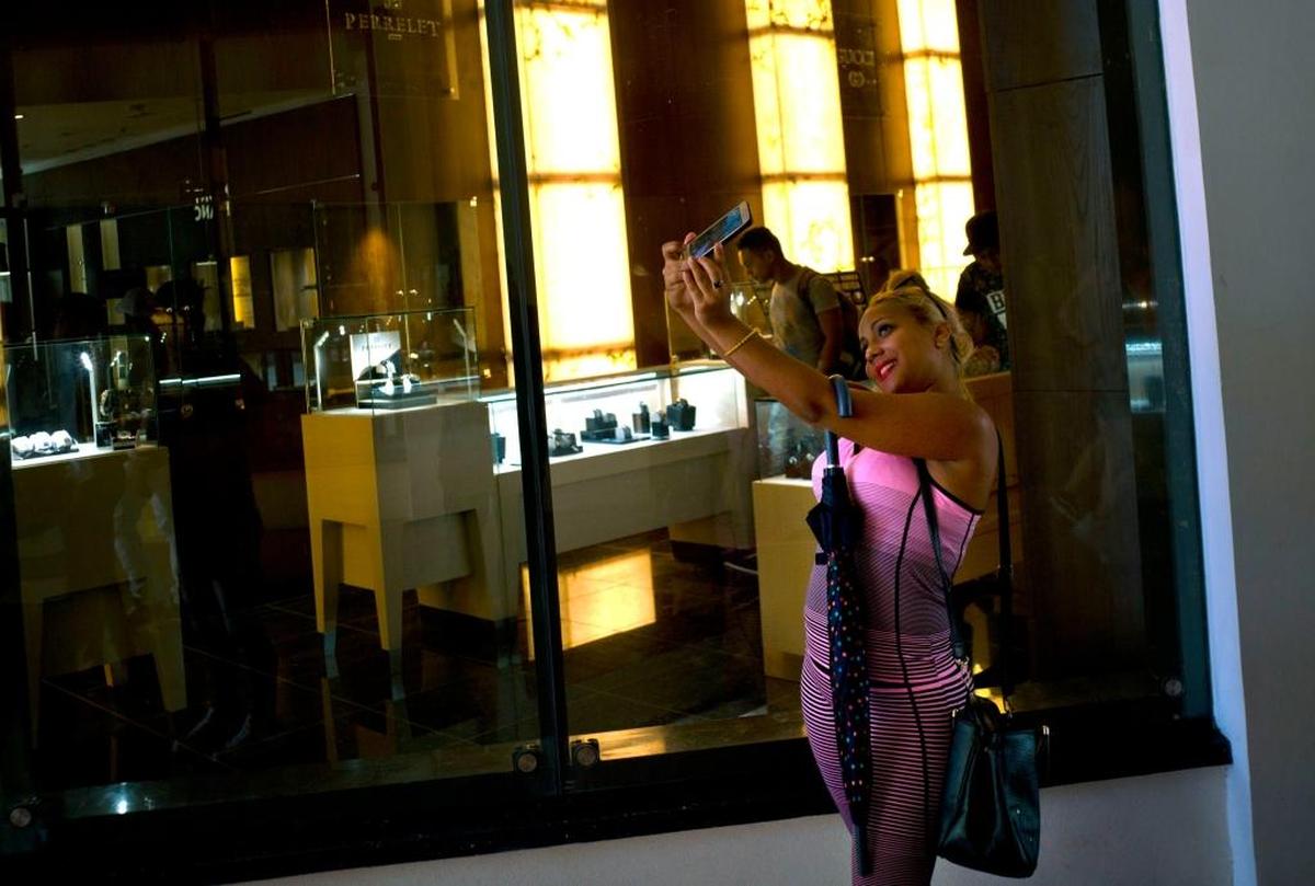A Cuban girl takes a selfie in front of a window of a luxury store at the Manzana de Gomez Kempinski, a new five-star hotel in Havana. It’s operated under a management contract with Gaviota, a Cuban military hotel brand.
