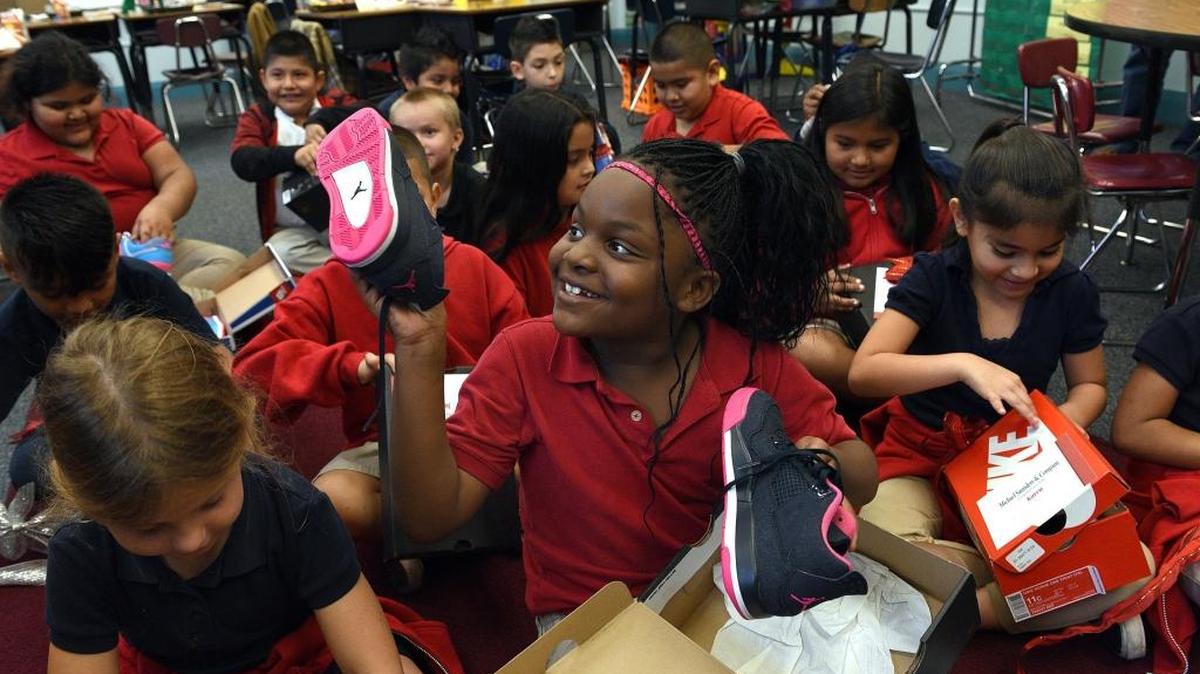 Serenity King holds up a brand new pair of shoes with a smile. Christmas came early for a class of second graders at Manatee Elementary whose teacher, Sandra Patterson, surprised them with brand new shoes.