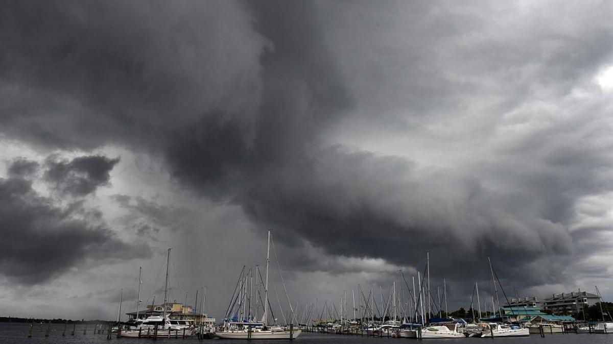 File: Rain-bearing clouds roll up the Manatee River seen behind the sails of sailboats moored at Regatta Pointe in Palmetto.