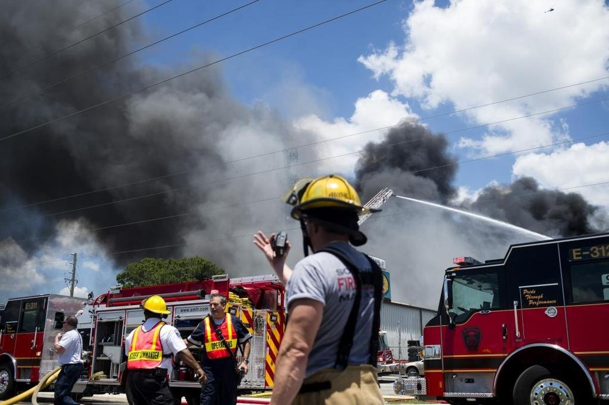Firefighters and other emergency crews respond to the scene of a large fire at Callaghan Tire on Thursday afternoon in Bradenton. Smoke billowed high into the air with reported sightings as far as St. Petersburg.
