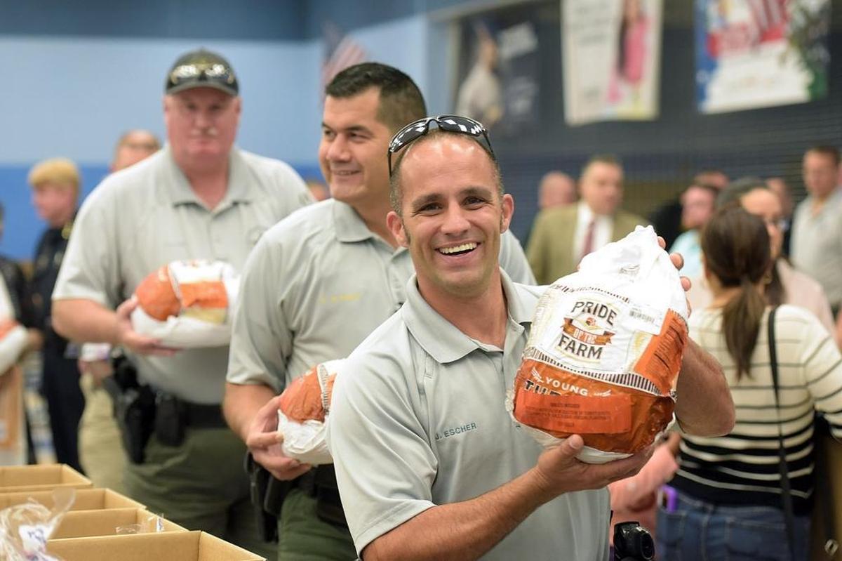 Deputy Joshua Escher smiles as he helps pack turkeys at Lincoln Middle School on Wednesday.