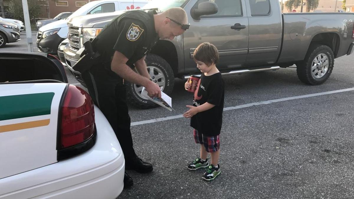 Manatee County Sheriff’s Office deputy George Schrenk hands J.R., 4, a coloring book after letting the boy sit in his patrol car during a dinner break Wednesday night.