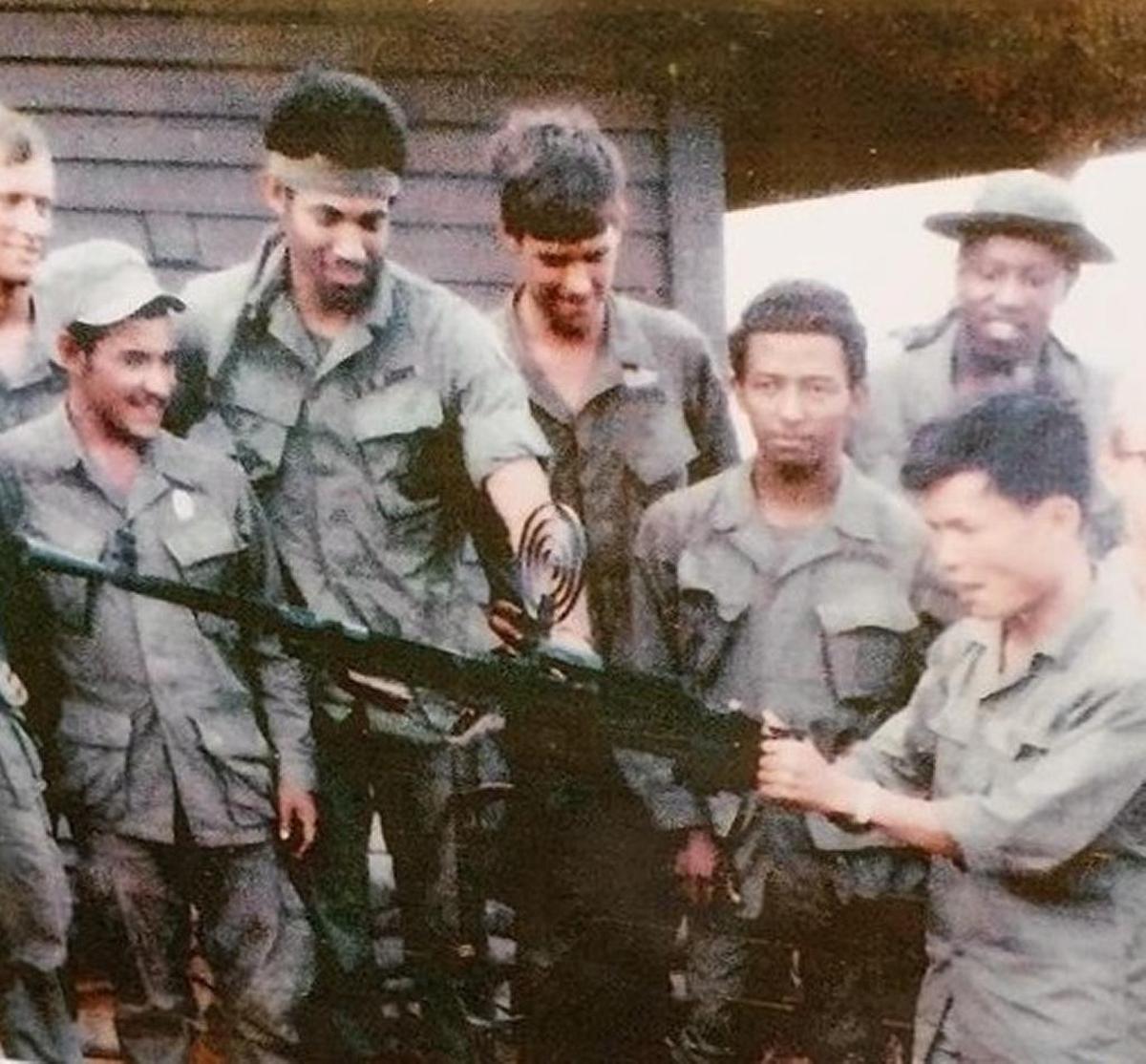 Tony Morton and other members of the 7th Squadron of the 17th Air Cavalry look at a captured North Vietnamese anti-aircraft machine gun.