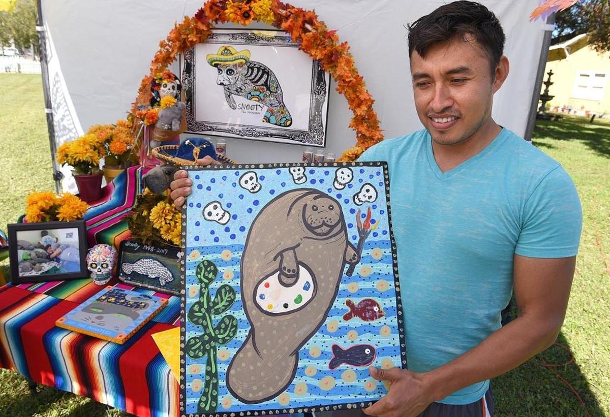 Alfredo Garcia holds his Snooty artwork, which will be placed upon the shrine to Snooty. The Village of the Arts will sell off all of the artwork honoring Snooty after the Day of the Dead celebration and donate the proceeds to the manatee rehab program at the South Florida Museum.