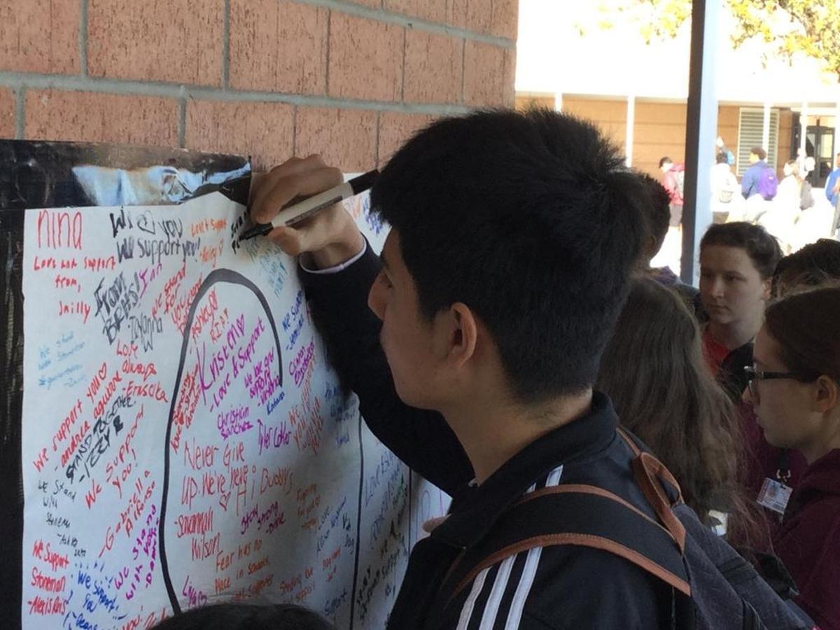Students at Braden River High School, in a 2018 student walkout, honor the Stoneman Douglas shooting victims by signing a memorial card.