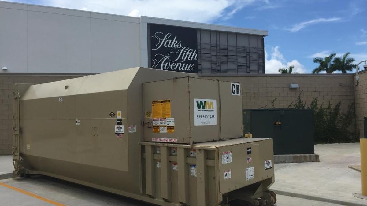 The shared trash compactor of dock C, where store and restaurant waste clashes, leaving cardboard typically unrecyclable.