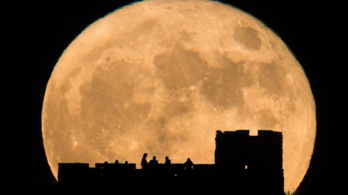 People watch the moon rise behind Coronado Heights near Lindsborg, Kan. on Nov. 14, 2016. (Travis Heying/The Wichita Eagle via AP)