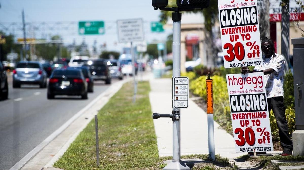 A man holds a sign advertising closing sale prices for hhgregg on Saturday off 14th Street West in Bradenton. hhgregg, the electronics and appliances retail chain, announced Friday night that it will be closing all stores.