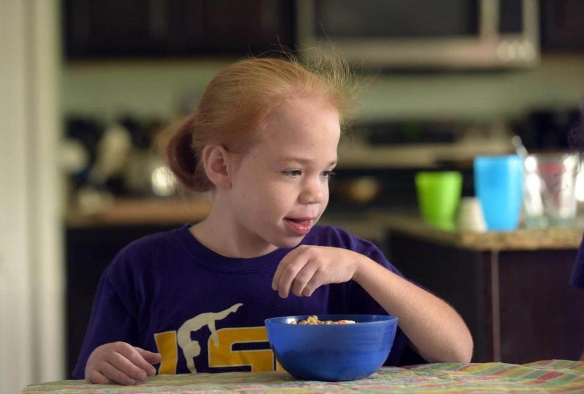 Fiona Humphrey smiles as she watches cartoons and eats cereal. Fiona was diagnosed with Sanfilippo syndrome; the family struggled for a long time finding the right diagnosis.