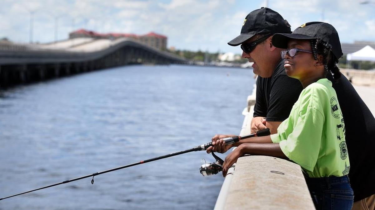 Palmetto Police Det. Richard Wilson fishes with Jaylan Powell, 10, on the Green Bridge Pier during the bridging the gap event for local youth and law enforcement.