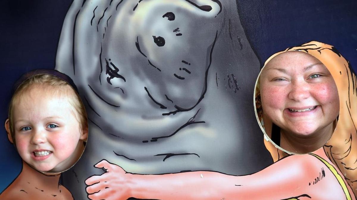 Miracle McLaughlin, 4, and Jewelette McLaughlin pose with a painting sign of Snooty. Hundreds of children and adults wish Snooty the manatee a happy birthday Saturday at Parker Aquarium.