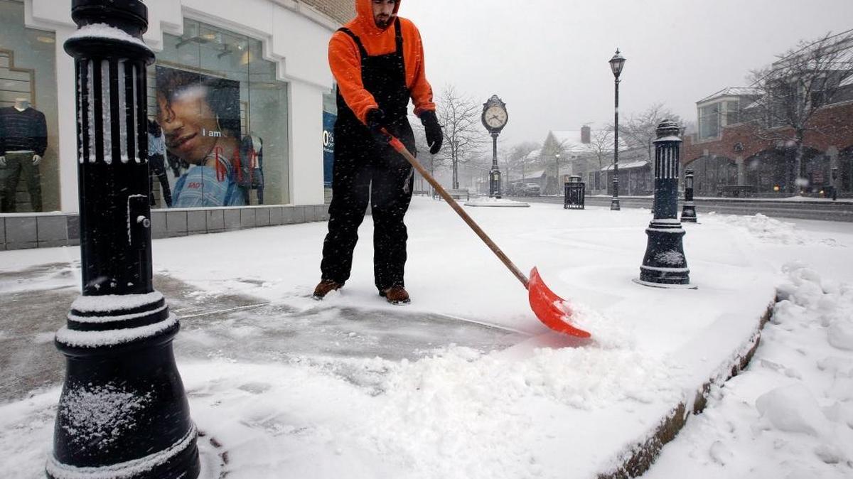 Zach MacGregor, of Framingham, Mass., clears snow from a sidewalk during Thursday’s snowstorm.