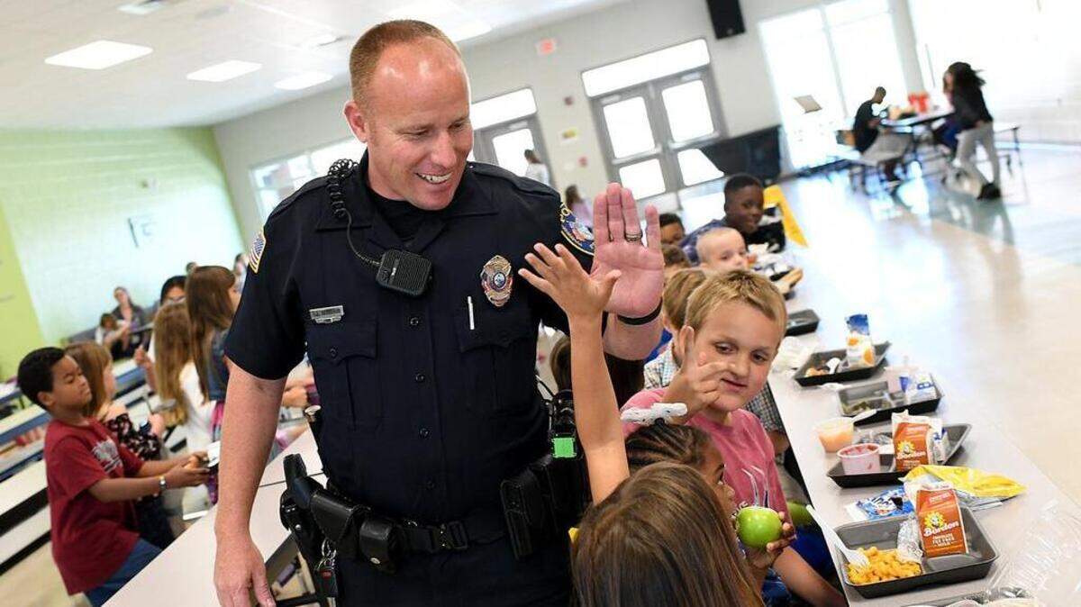 Bradenton Police officer Rusty Ackerman gives high fives to students at lunch as he fills in as a school resource officer at Miller Elementary School earlier this year. Bradenton voted to help the district fund police officers as school resource officers, but at a lower cost to the city than the district proposes.