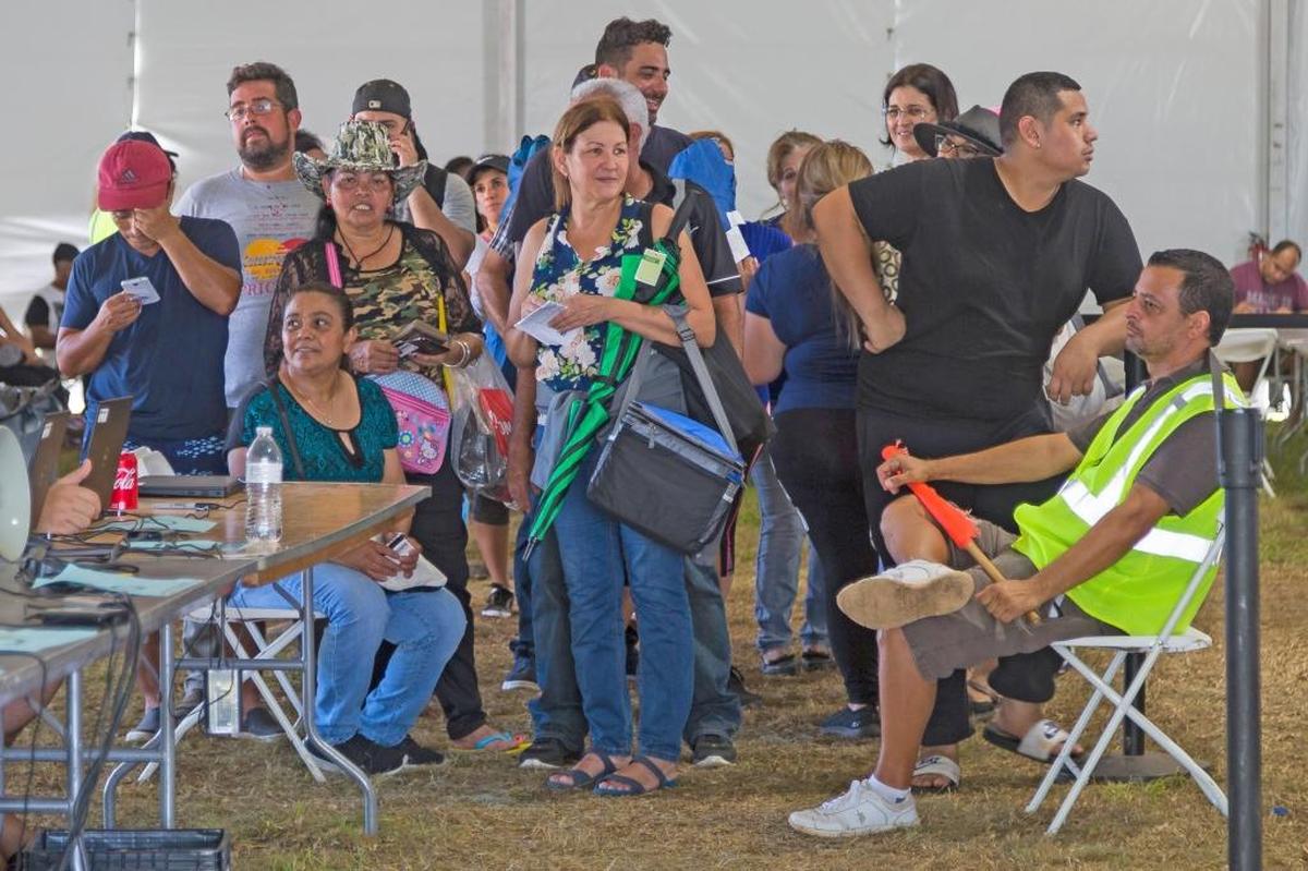 People arrive to the registration table in hopes of receiving aid from a post-hurricane disaster center at Tropical Park in Miami on Sunday, Oct. 15, 2017.