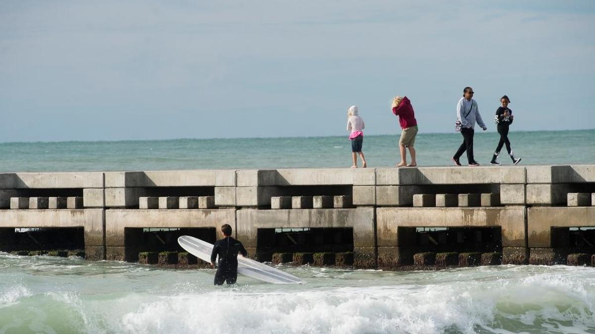Beachgoers walk on a completed beach groin on Cortez Beach on Friday in Bradenton Beach. The beach groins have been completed after nearly two years of construction, and help to protect the sand from strong waves coming from the Gulf of Mexico.
