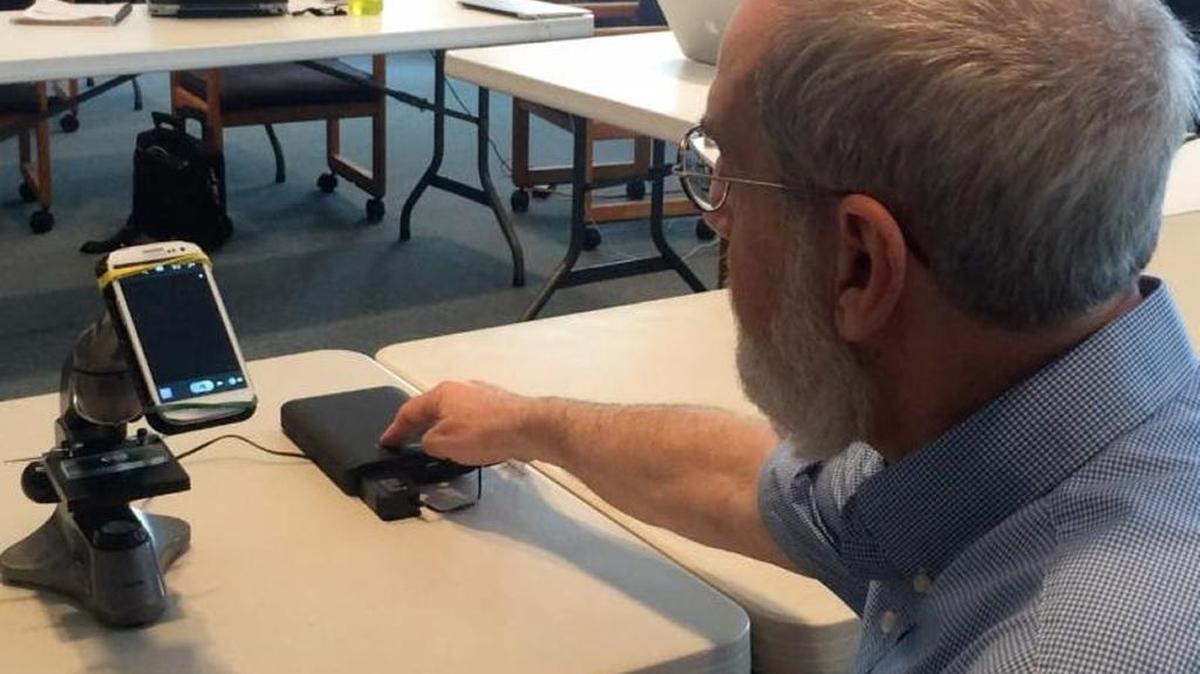 Dr. Wayne Litaker uses a prototype of the microscope-smartphone unit. The red tide app will be able to identify the virus’ presence in the water using facial-recognition software.