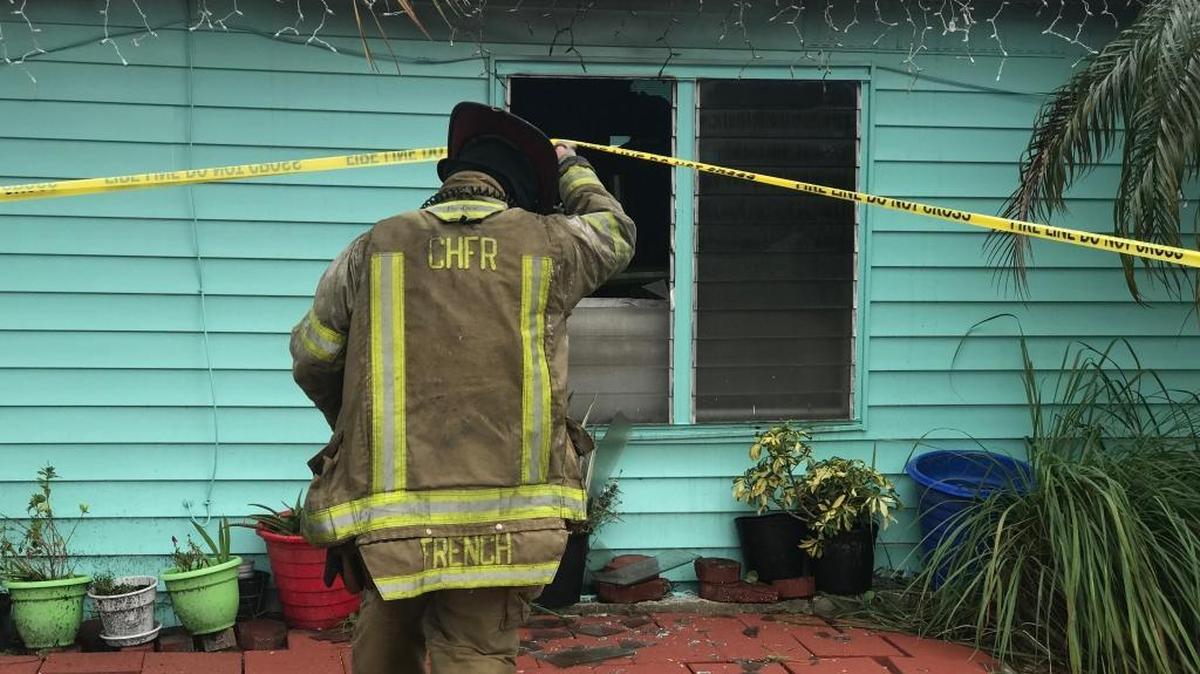A firefighter crosses the fire line to inspect a mobile home in the 100 block of Main Drive, Bradenton, that caught fire Saturday morning.