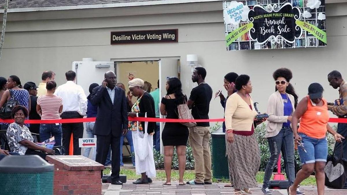 Voters stand in line outside the North Miami Public Library waiting to cast ballots during early voting, Friday, Nov. 4.