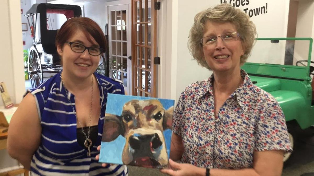 Melissa Dagenais, left, curator of the Manatee County Agricultural Museum and museum director Diane Ingram show off “Pauline,” a cow painted by an Easter Seals student named Ashley. Pauline will be on exhibit at the museum in Palmetto Friday along with 30 other Easter Seals’ pieces.