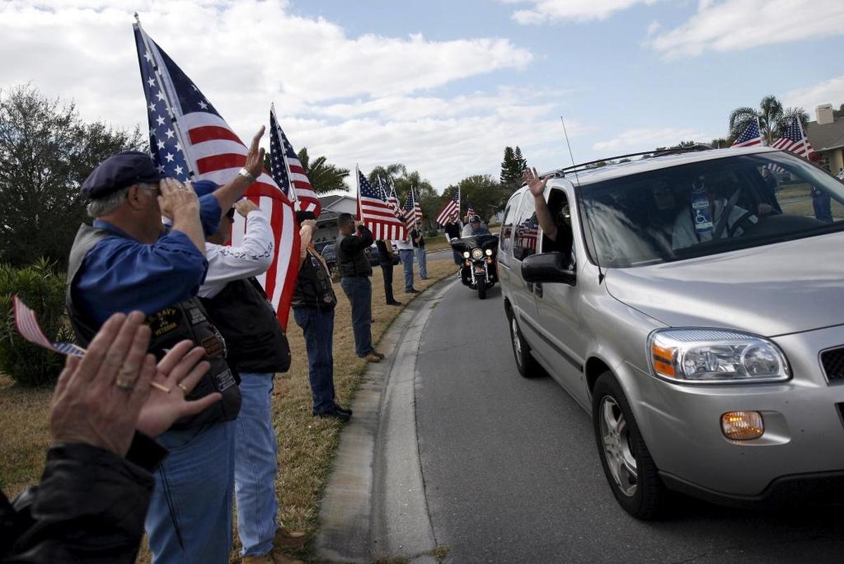First Sgt. Aaron Cornelius, who was wounded and blinded by an IED in Iraq, waves as his wife drives him home through a flag line of Patriot Guard riders to welcome him home in 2009.