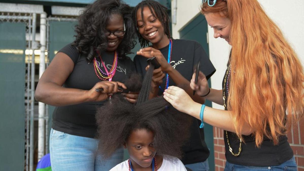 The Kiwanis Club held their sixth annual Christmas in August event at McKecknie Field in Bradenton on Saturday. More than 500 children who are categorized as homeless were given backpacks loaded with school supplies as well as treated to other services and entertainment. Kids also took advantage of medical and dental care as well as haircuts. Here Fatima Hakim, is getting her hair braided by, from left: Kaneka Edwards, Tiki Miller, and Rachel Bowman.