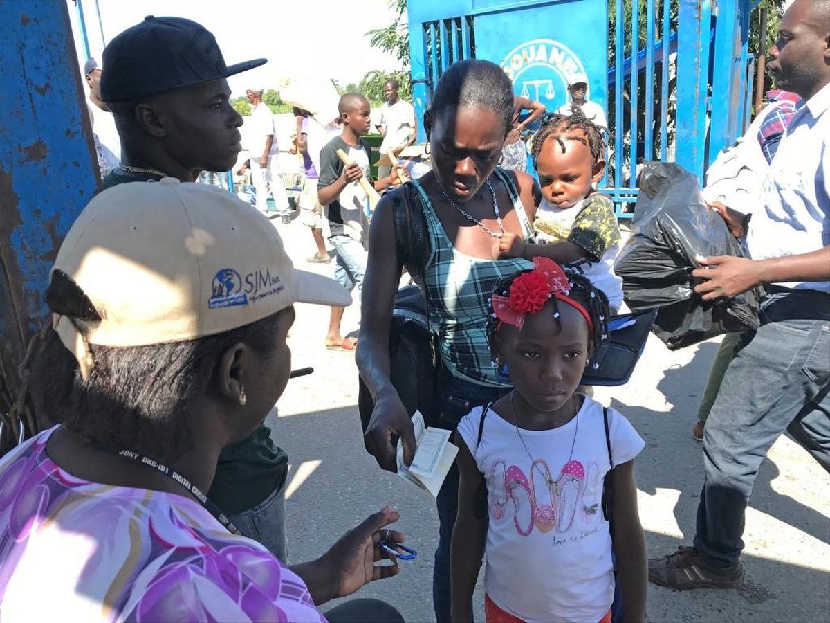 A child protection worker with Haiti’s child welfare agency, the Institut du Bien-Être Social et de Recherches or IBESR, questions a Haitian monther along the Haiti-Dominican border in Ouanaminthe who is headed to Dajabón in the Dominican Republic. Child protection agents routinely monitor the border in an effort to clamp down on trafficking and ensure that children have legal documents to transit.