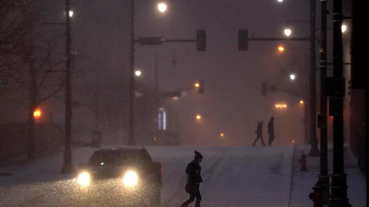 Pedestrians walk across a snowy street in downtown Kansas City, Mo., on Saturday, Dec. 17, 2016. A winter storm of snow, freezing rain and bone-chilling temperatures hit the nation's mid-section and East Coast on Saturday and Sunday.