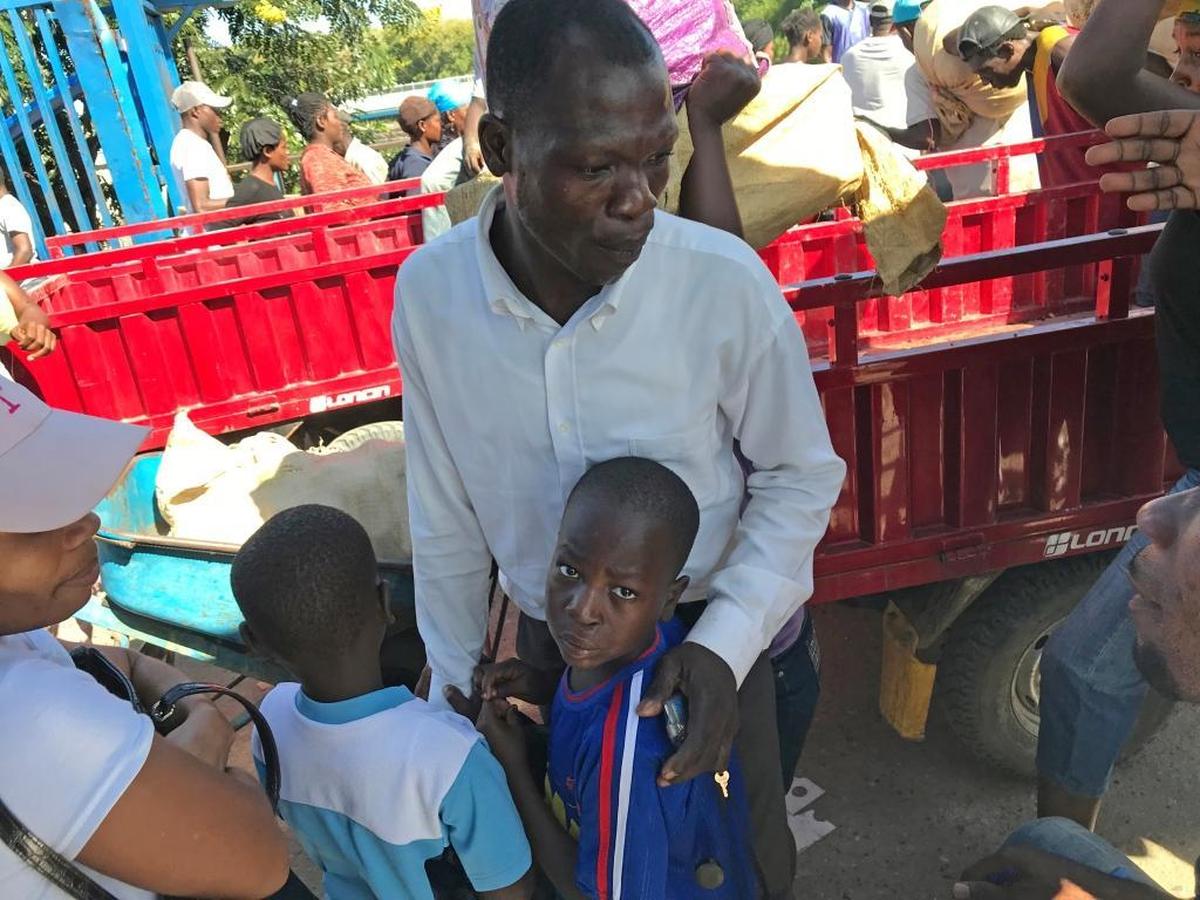 Two young boys who are illegally being taken to the Dominican Republic hold onto to their father while he’s being questioned by child protection workers with the United Nations’ International Organization for Migration and Haiti’s child welfare agency, the Institut du Bien-Être Social et de Recherches or IBESR.