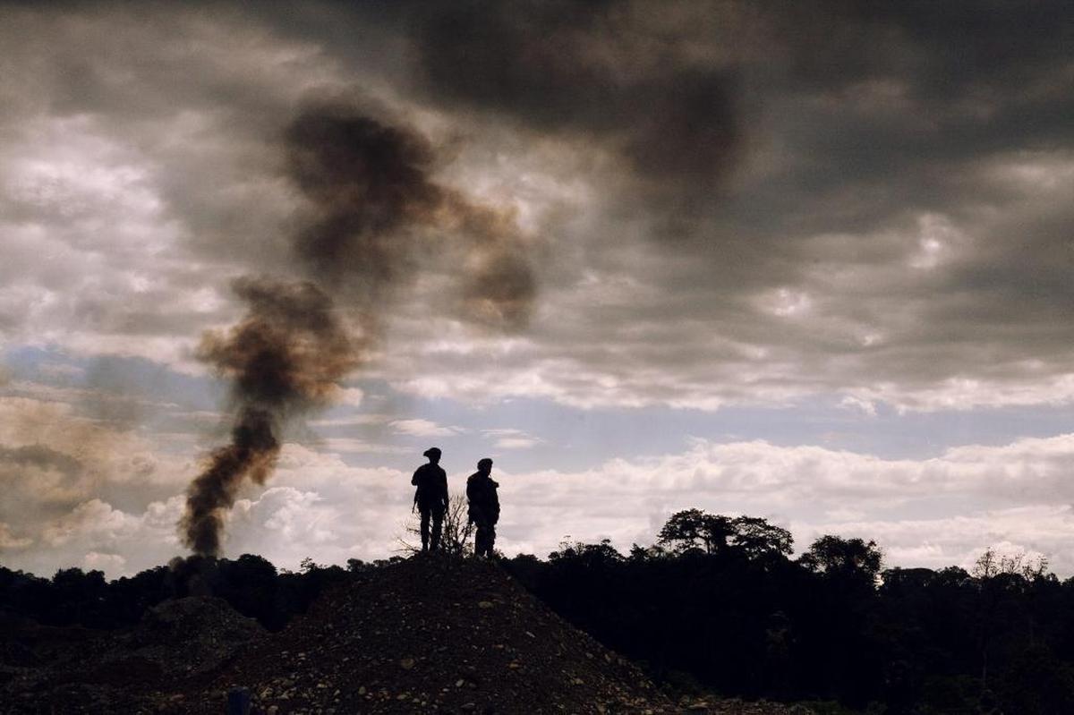 Policemen stand watch in southwestern Colombia after authorities destroyed backhoes involved in illegal gold mining operations.