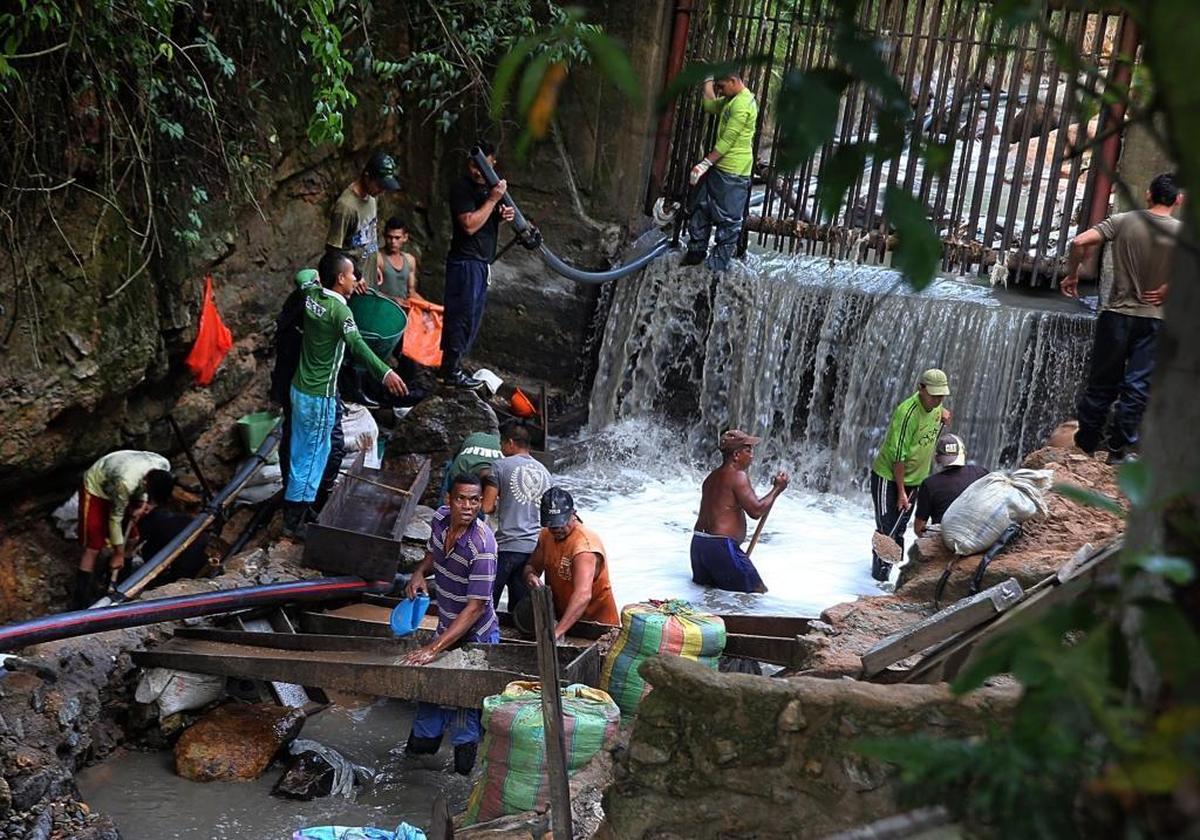 A group of people including women and children search for gold on fine sand contained in the water dumped out to a river called Cianurada -- “cyanide-filled river” -- after processing at the Gran Colombia Gold Corporation factory in the gold mining town of Segovia, Antioquia department, in Colombia, on Monday May 08, 2017.