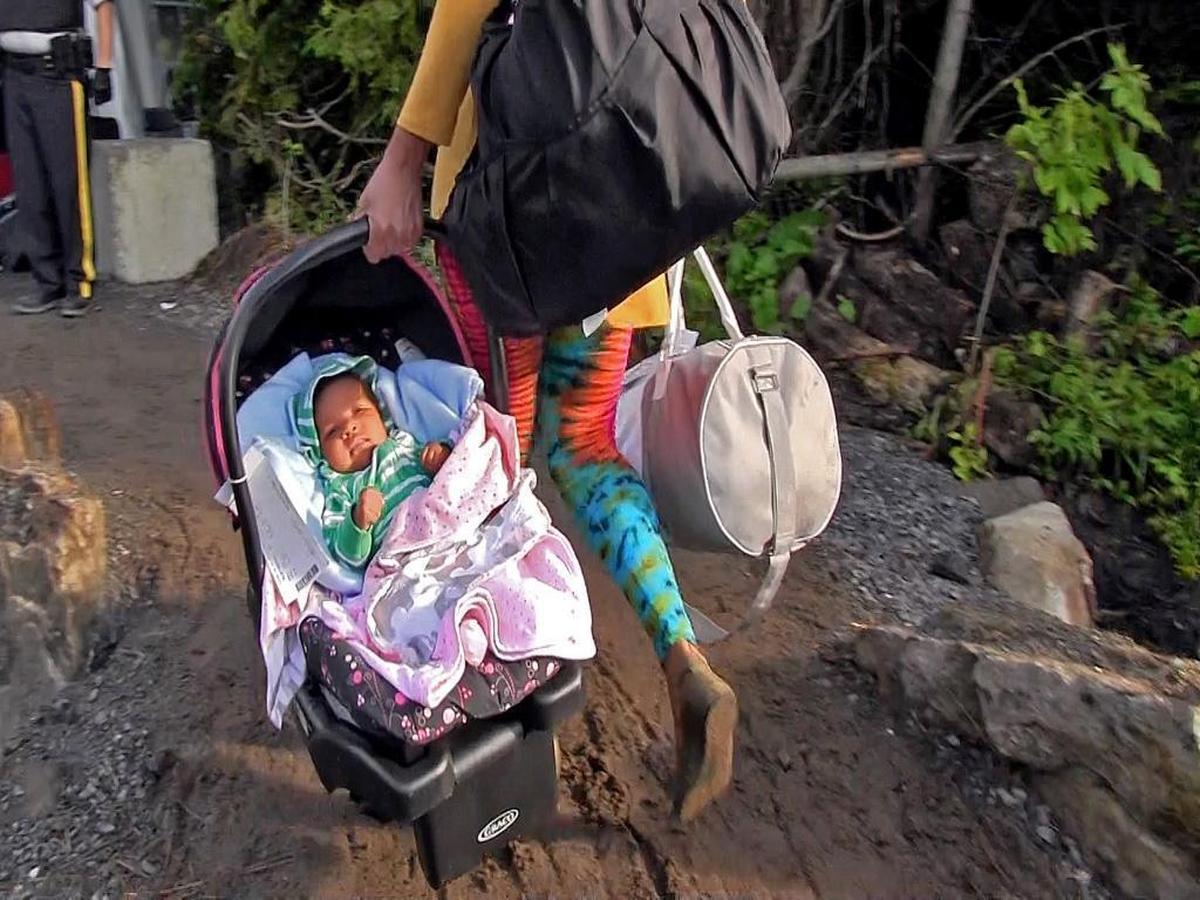 Rebecca Paul and her baby girl walk across a dirt and gravel path to leave the U.S. and walk across to Canada at Roxham Road on Sunday, August 13, 2017. More than 3,800 asylum seekers have crossed illegally into Canada during the first two weeks of August.