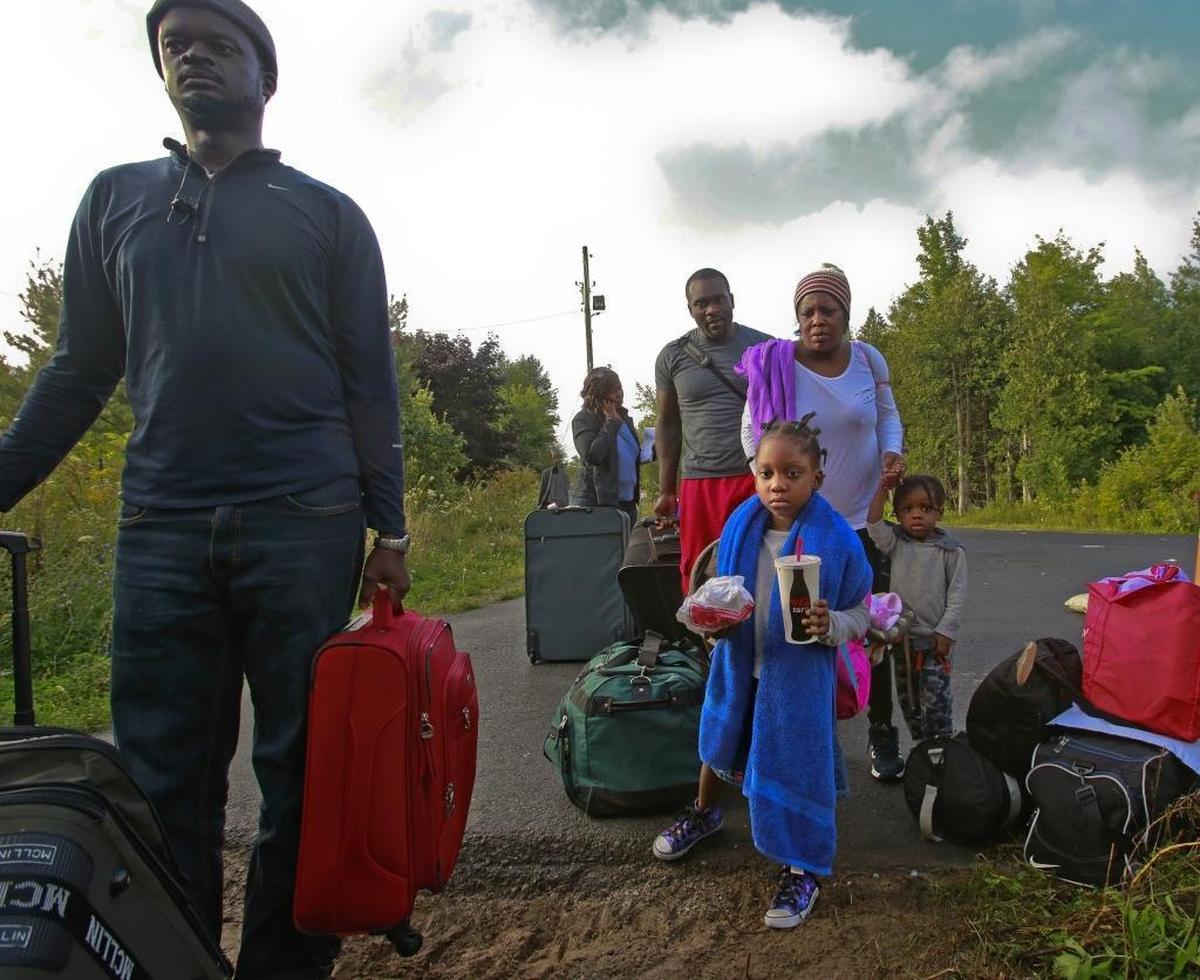 Haitian migrants prepare to cross illegally into Canada at the border along Roxham Road in Champlain, N.Y., on Sunday, August 13, 2017. They said fear of deportation under the Trump administration drove them to leave the U.S.