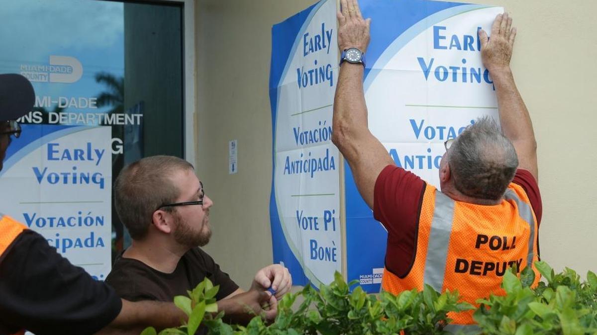 Employees hang early voting signs as they conduct early voting training for the Nov. 8 general election at the Miami-Dade County Elections Department, Wednesday, Oct. 12, 2016, in Doral.