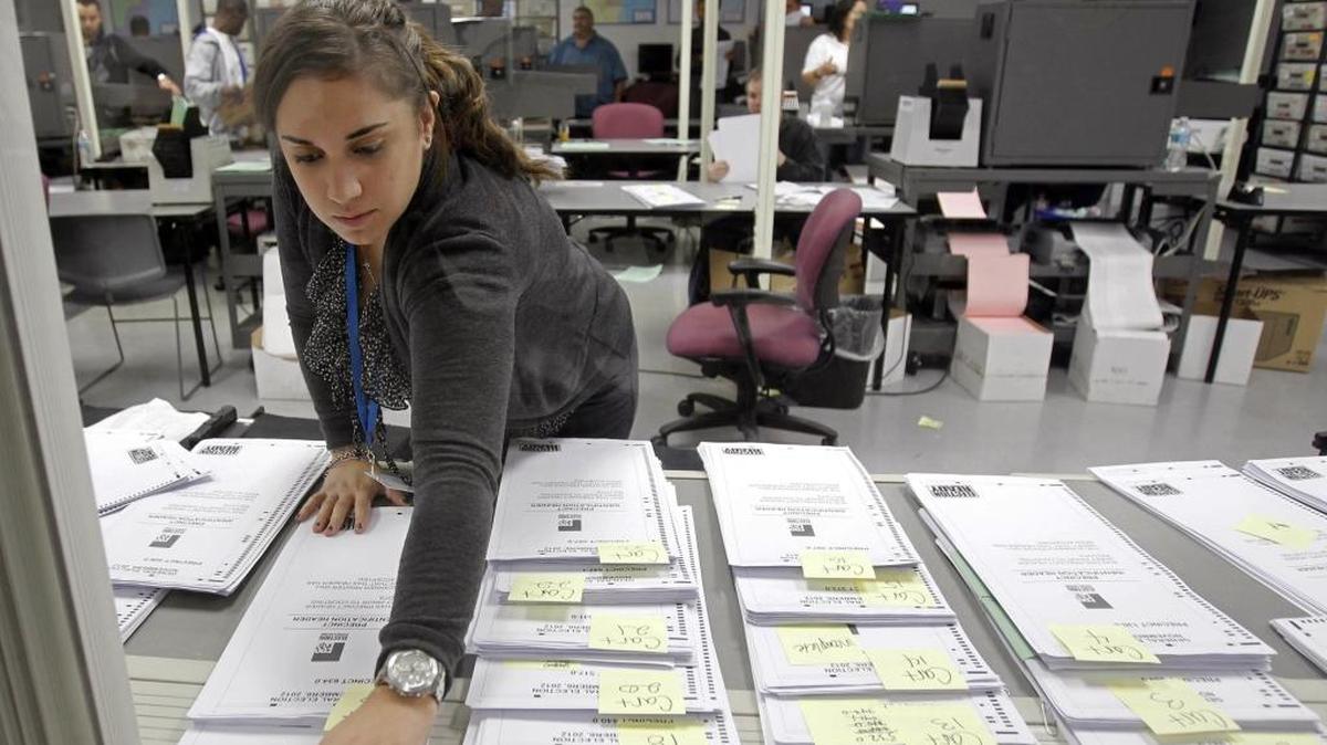 In this 2012 file photo, a Miami-Dade Elections worker marks a group of absentee ballots in Doral.