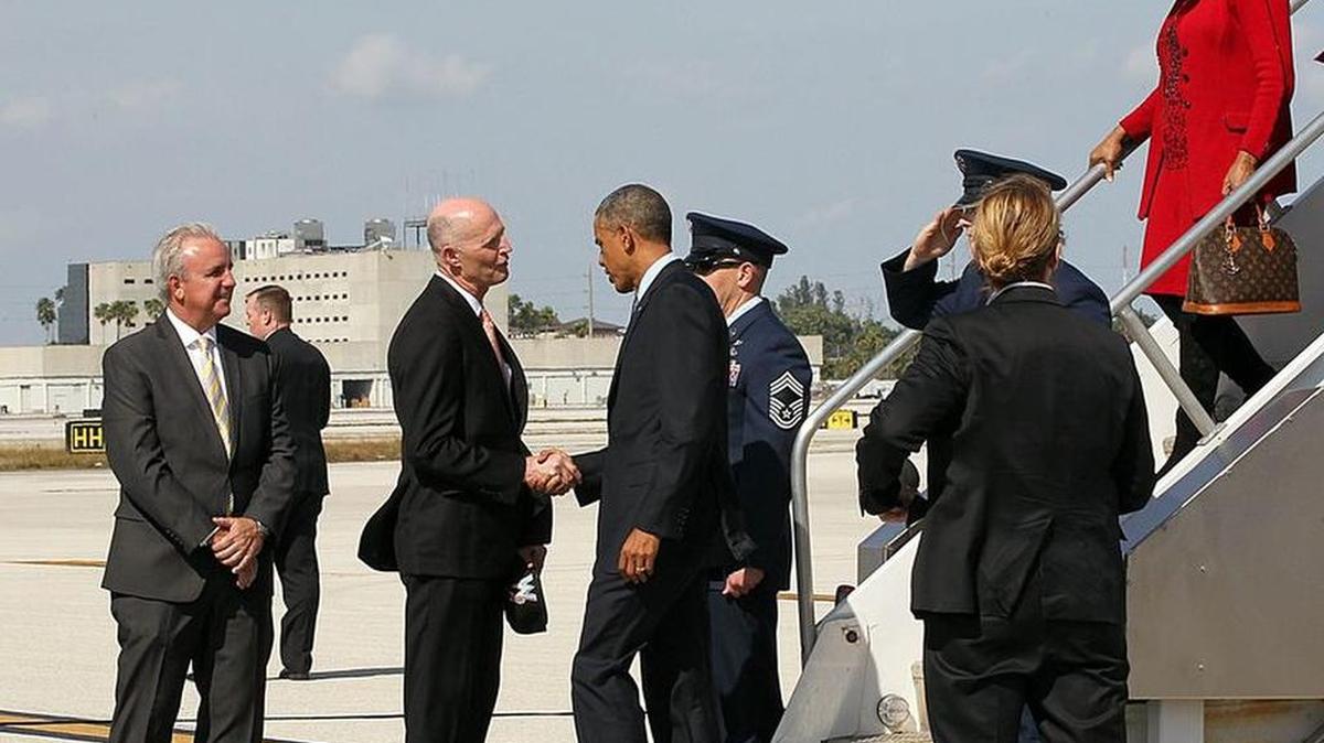 U.S. President Barack Obama is welcomed by Miami-Dade County Mayor Carlos Gimenez and Florida Governor Rick Scott, as he arrives at Miami Internation with Congresswoman Frederica Wilson, for a town hall meeting on immigration at Florida International University on Wednesday Feb. 25, 2015.