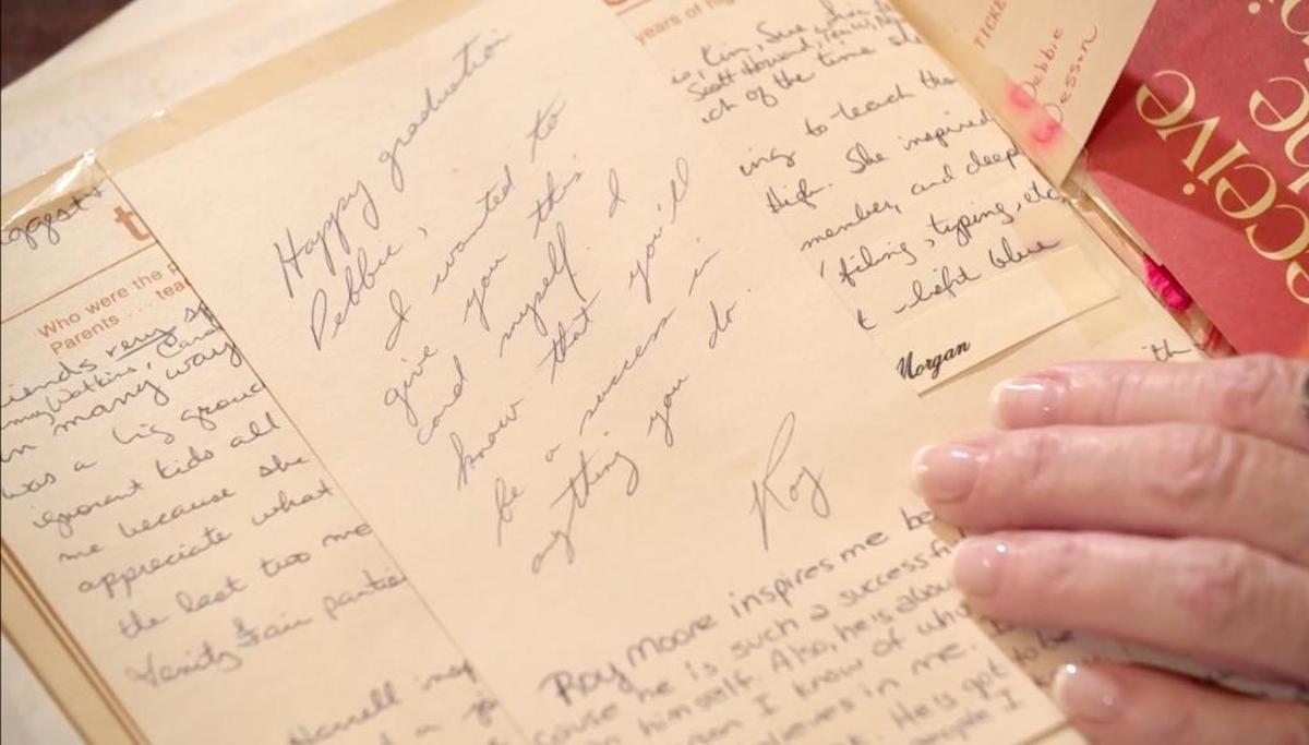 Debbie Wesson Gibson shows what she says is a graduation card from Roy Moore. She says he handed it to her during her high school graduation ceremony in 1981. Underneath is Gibson's own note about what Moore meant to her at the time.