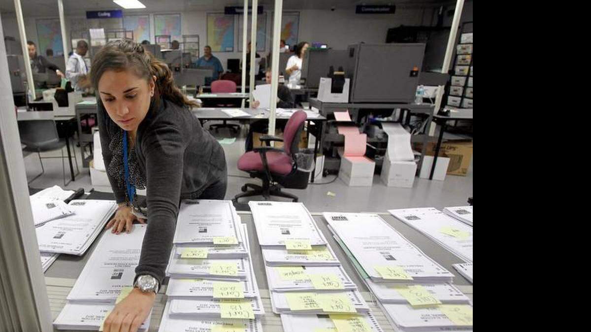 A Miami-Dade elections worker marked a group of absentee ballots in 2012. ALAN DIAZ AP