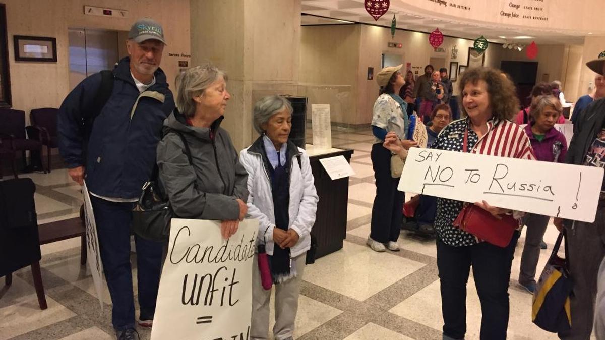 Demonstrators hold signs outside the Florida Senate chamber to encourage the state’s 29 electors to oppose Donald Trump for president in the Electoral College vote on Monday, Dec. 19, 2016.