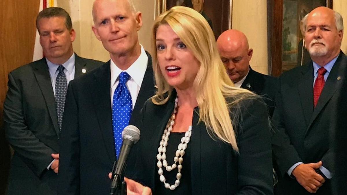 Florida Attorney General Pam Bondi speaks as Florida Gov. Rick Scott, second from left, listens during a news conference at the state capitol on April 11 in Tallahassee.